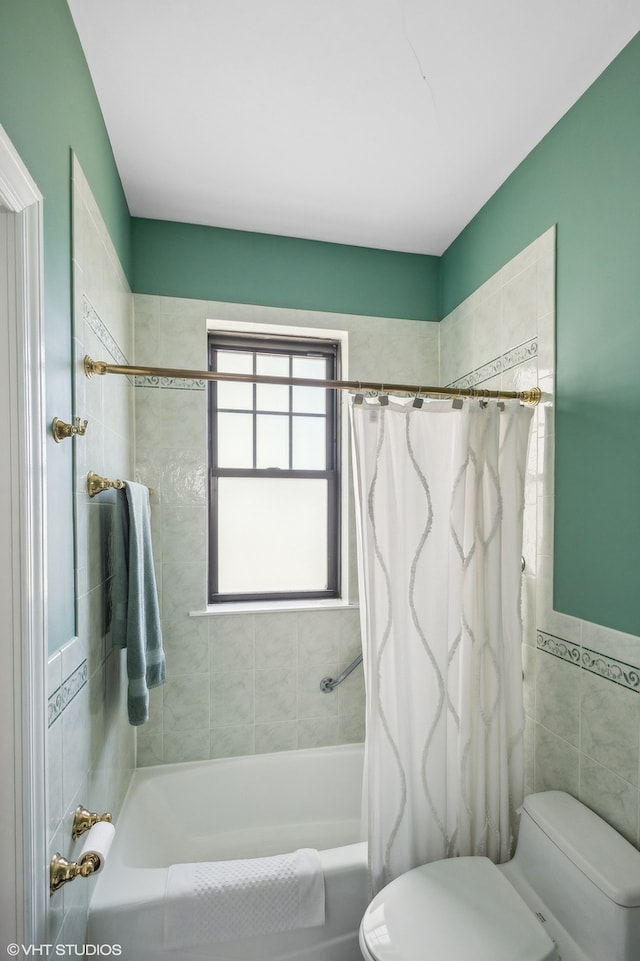 bathroom featuring tile walls, shower / bath combo with shower curtain, and toilet