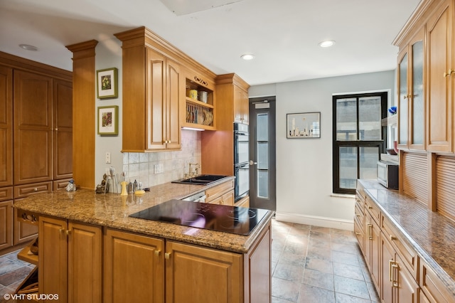 kitchen featuring black appliances, light stone countertops, tasteful backsplash, sink, and kitchen peninsula