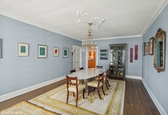 dining area with dark wood-type flooring, ornamental molding, and a chandelier