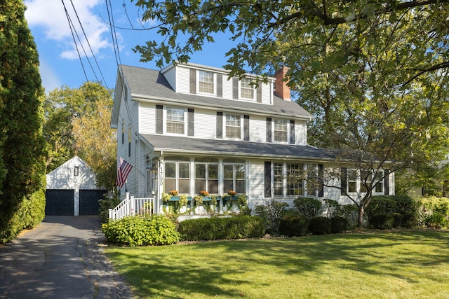 view of front of property with an outbuilding, a sunroom, a front yard, and a garage