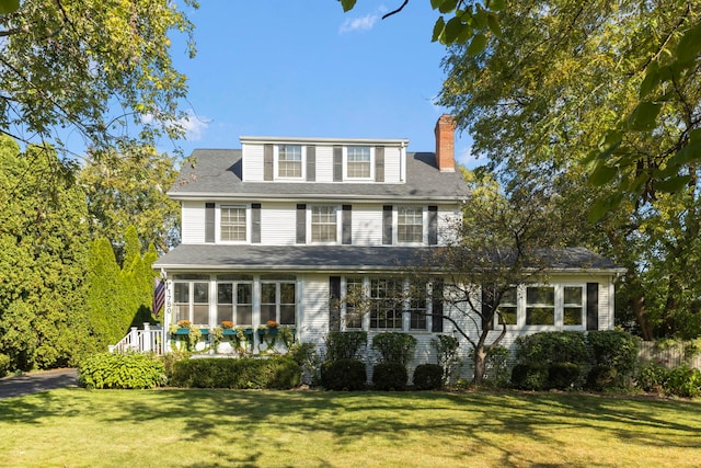 view of front of home featuring a sunroom and a front lawn