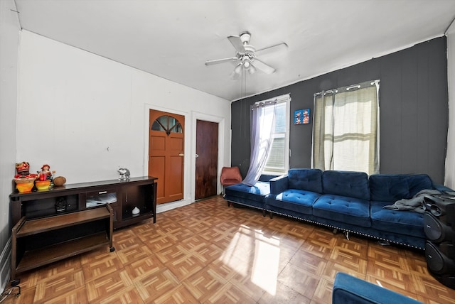 living room with wooden walls, parquet flooring, and ceiling fan