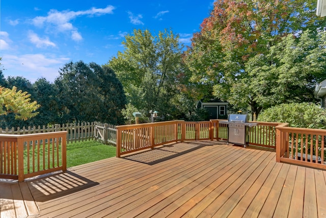 wooden deck featuring a lawn and a grill