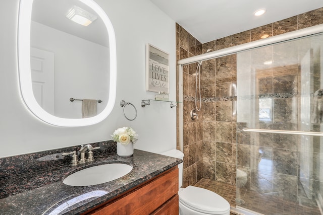 bathroom with vanity, toilet, and a shower with door