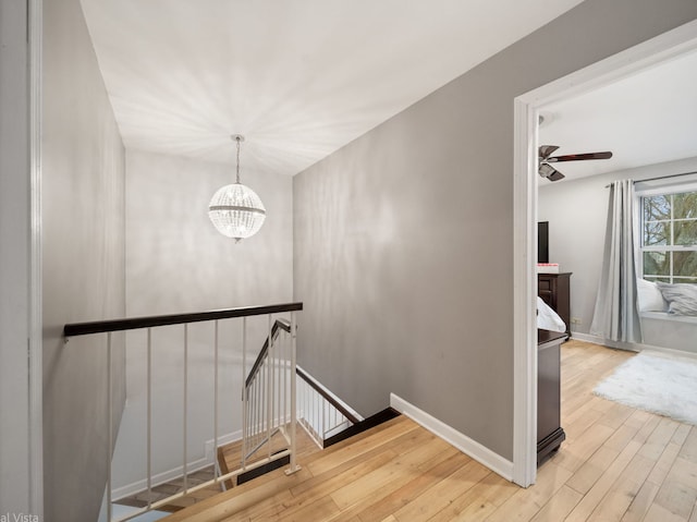 staircase featuring hardwood / wood-style flooring and ceiling fan with notable chandelier