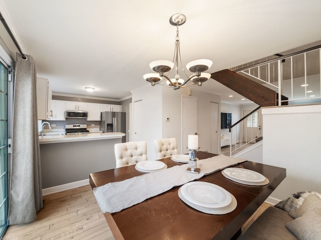 dining room featuring an inviting chandelier, ornamental molding, sink, and light wood-type flooring