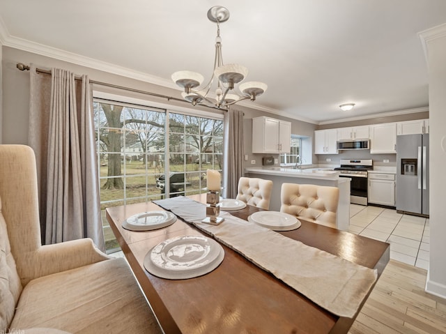 dining space featuring ornamental molding, sink, a notable chandelier, and light hardwood / wood-style floors