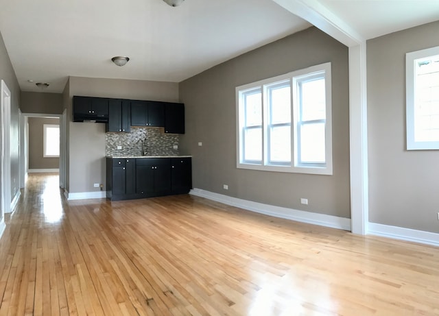 kitchen with decorative backsplash, light hardwood / wood-style floors, and sink