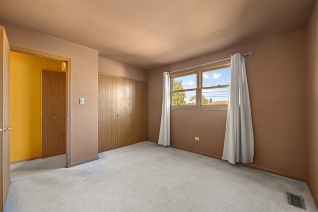 unfurnished bedroom with a closet and light colored carpet