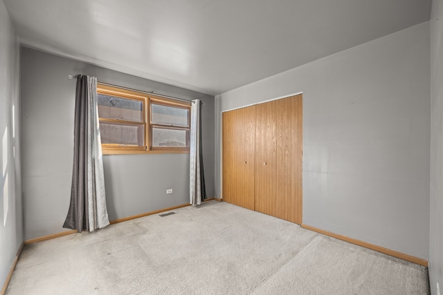 unfurnished bedroom featuring light colored carpet and a closet