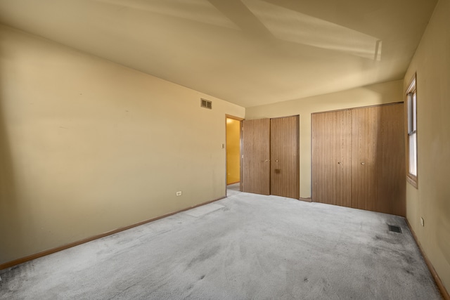 unfurnished bedroom featuring carpet flooring and multiple closets