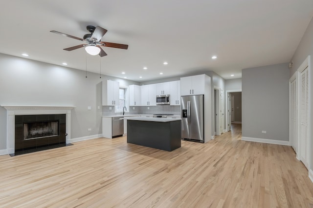 kitchen with decorative backsplash, a center island, stainless steel appliances, light hardwood / wood-style floors, and white cabinetry