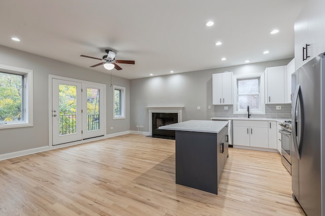 kitchen with a healthy amount of sunlight, a center island, stainless steel appliances, and white cabinets