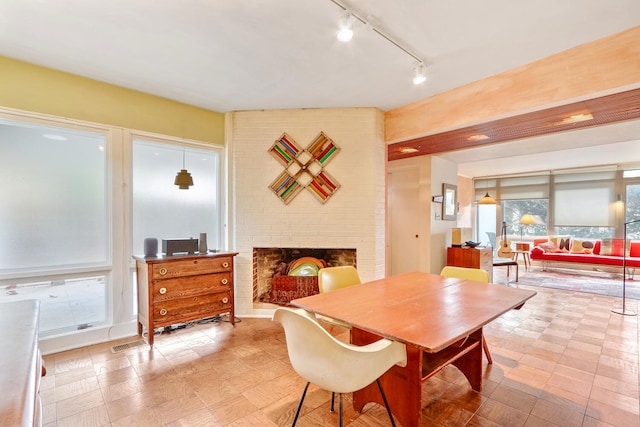 dining room with track lighting and a brick fireplace