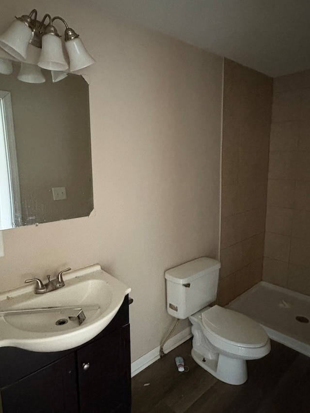 bathroom featuring a tile shower, hardwood / wood-style floors, vanity, and toilet