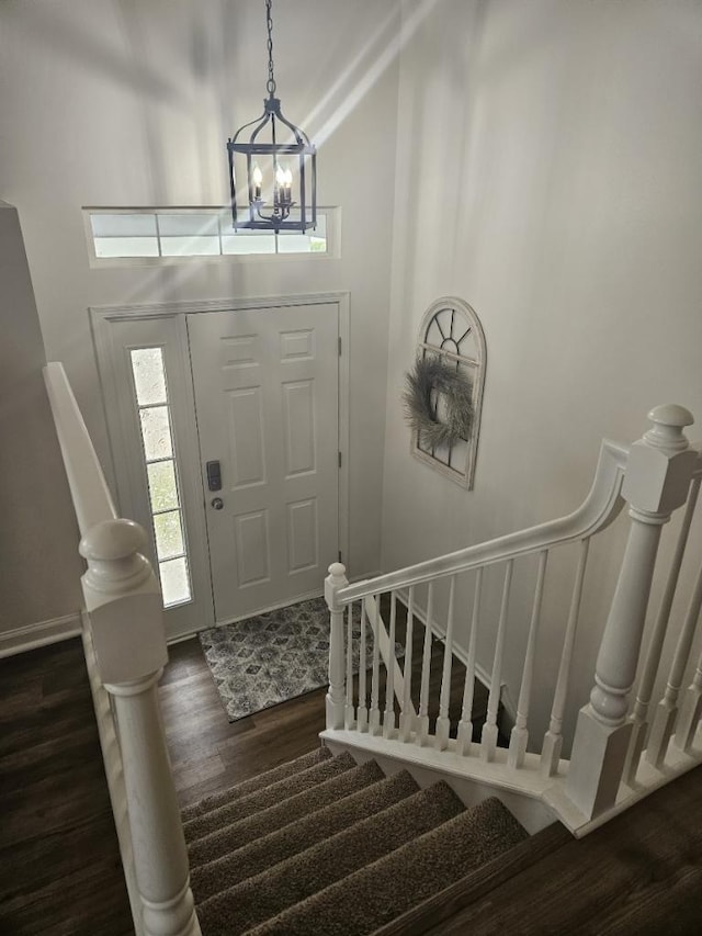 entryway featuring an inviting chandelier, dark wood-type flooring, and a high ceiling