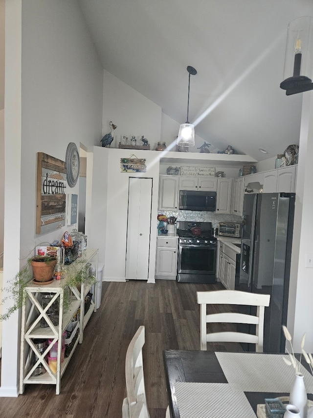 kitchen with vaulted ceiling, tasteful backsplash, pendant lighting, stainless steel appliances, and dark hardwood / wood-style floors