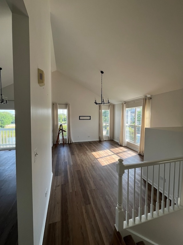 interior space featuring vaulted ceiling, a notable chandelier, plenty of natural light, and dark wood-type flooring