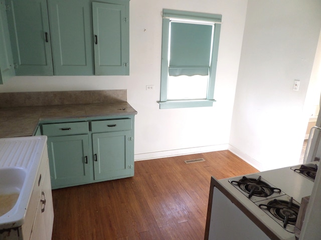 kitchen with white gas range oven, green cabinets, and dark hardwood / wood-style flooring