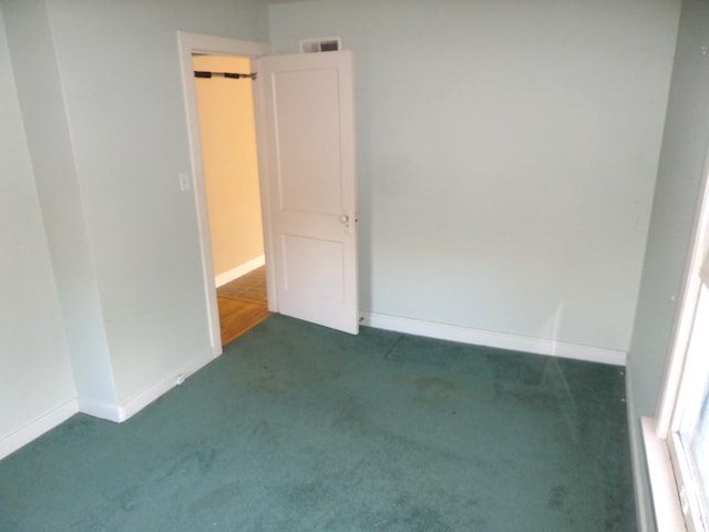 unfurnished room featuring dark carpet