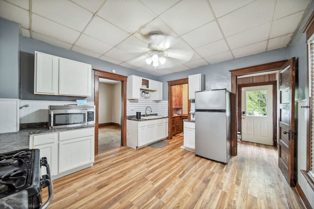 kitchen featuring backsplash, a drop ceiling, stainless steel appliances, sink, and light hardwood / wood-style floors