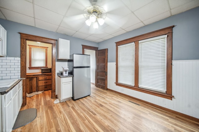 kitchen featuring white cabinetry, a drop ceiling, ceiling fan, stainless steel fridge, and light hardwood / wood-style floors