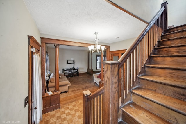 staircase featuring a notable chandelier and a textured ceiling