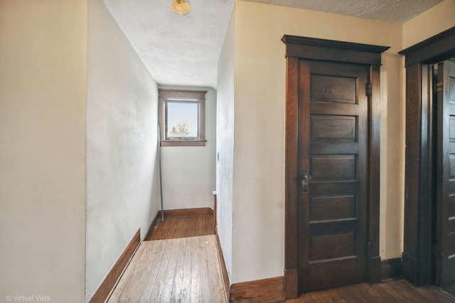 corridor with dark hardwood / wood-style flooring and a textured ceiling