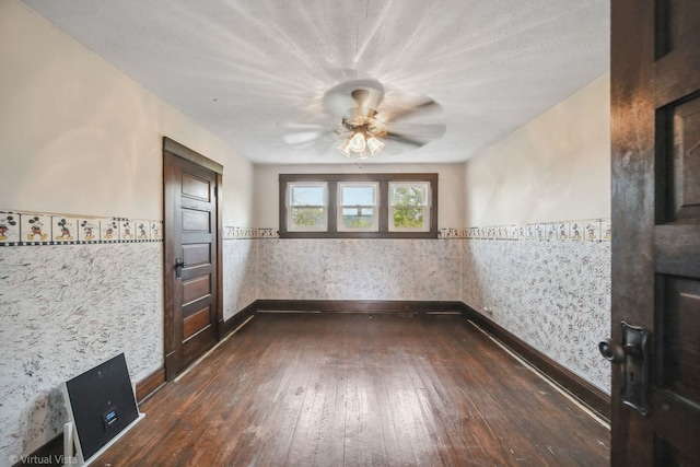 empty room featuring a textured ceiling, ceiling fan, and dark wood-type flooring