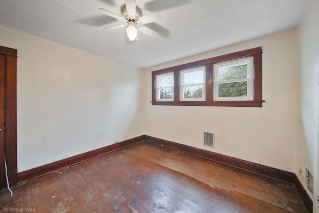 unfurnished room with ceiling fan, dark wood-type flooring, and a textured ceiling