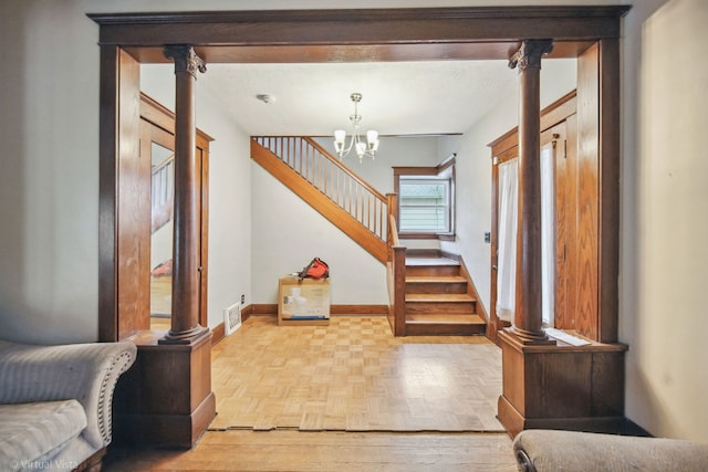 entrance foyer with ornate columns, light parquet floors, and an inviting chandelier