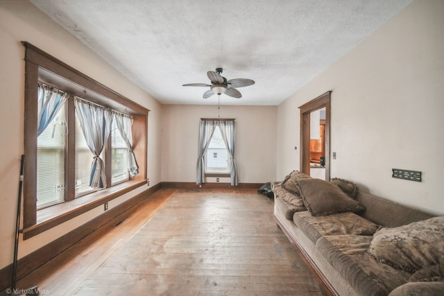 living room with hardwood / wood-style flooring, ceiling fan, and a textured ceiling