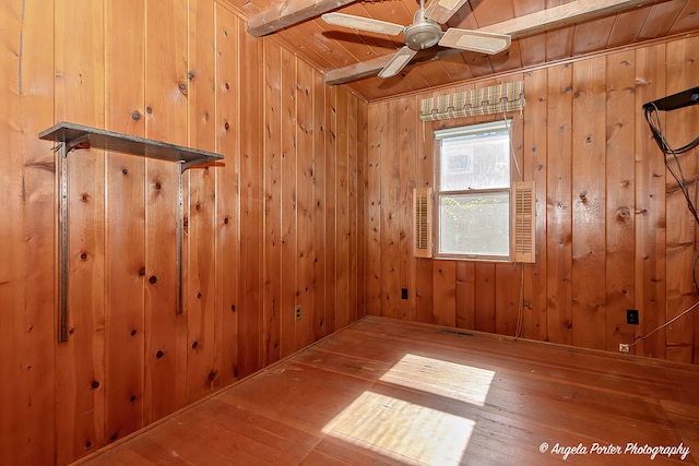 spare room featuring wood-type flooring, wood ceiling, wooden walls, and ceiling fan