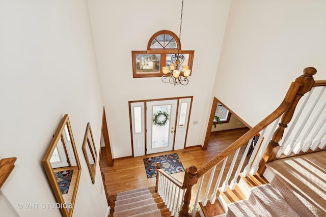 entrance foyer with a high ceiling, hardwood / wood-style flooring, and a chandelier