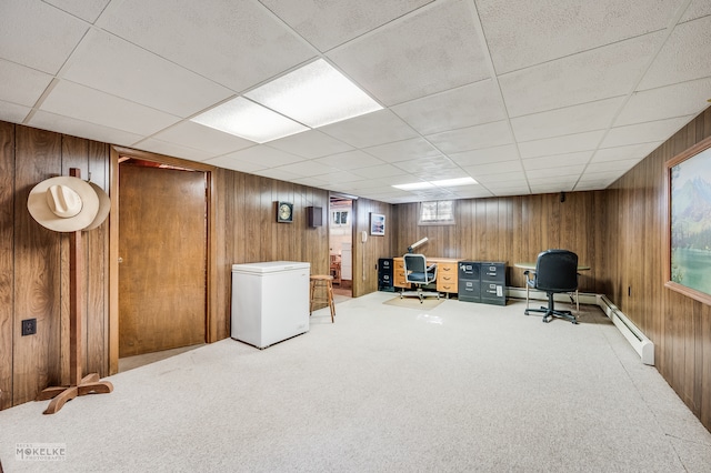 carpeted home office with wood walls, a baseboard heating unit, and a paneled ceiling