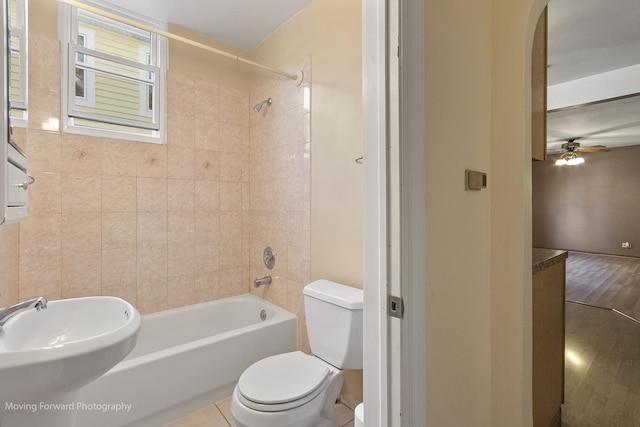 full bathroom with tile patterned floors, sink, tiled shower / bath combo, ceiling fan, and toilet