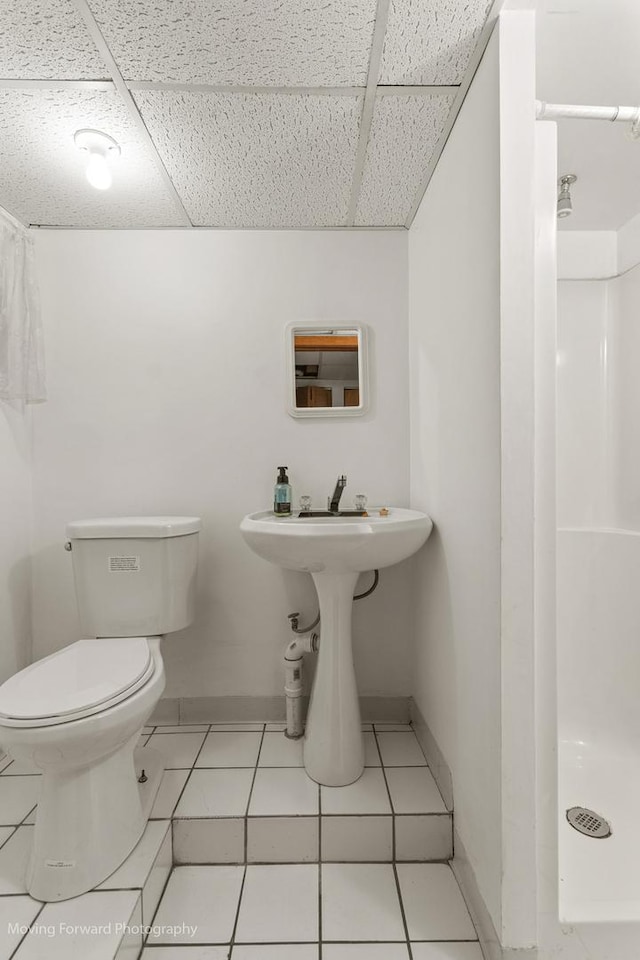 bathroom featuring tile patterned flooring, a shower, a paneled ceiling, and toilet