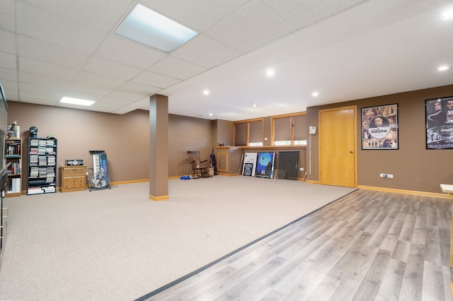 basement with a drop ceiling and light hardwood / wood-style flooring