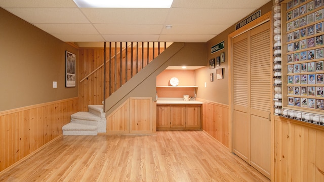 interior space with a paneled ceiling, hardwood / wood-style flooring, and wood walls