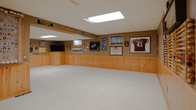 interior space featuring a paneled ceiling and wood walls