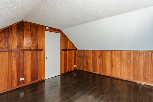 bonus room featuring lofted ceiling, dark hardwood / wood-style floors, and a textured ceiling