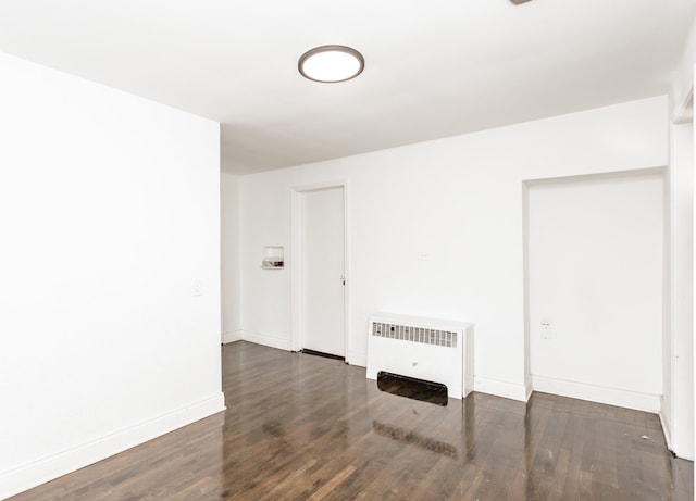 unfurnished room featuring radiator and dark hardwood / wood-style flooring