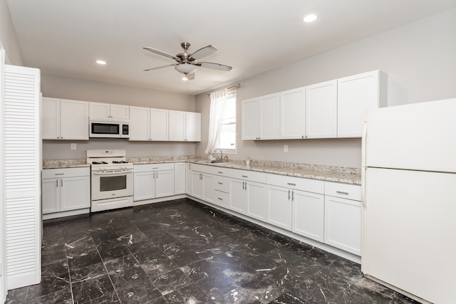 kitchen with ceiling fan, white appliances, sink, light stone counters, and white cabinets