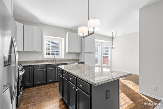 kitchen featuring pendant lighting, a center island, sink, dark hardwood / wood-style floors, and stainless steel appliances