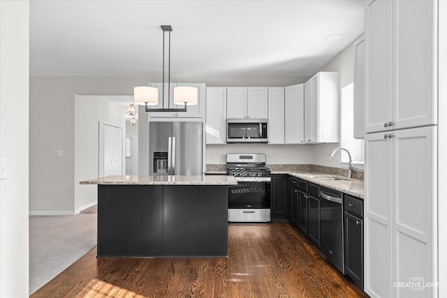 kitchen with sink, hanging light fixtures, dark wood-type flooring, stainless steel appliances, and a kitchen island