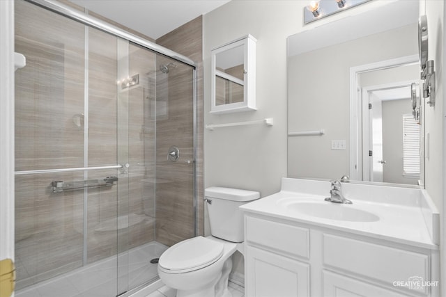 bathroom featuring a shower with door, vanity, and toilet