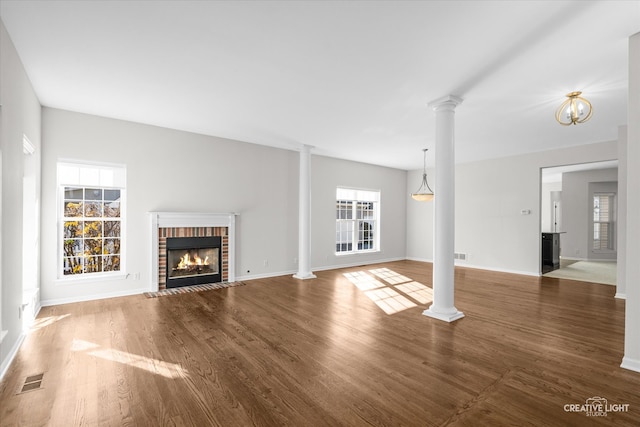 unfurnished living room with hardwood / wood-style flooring, ornate columns, and a fireplace