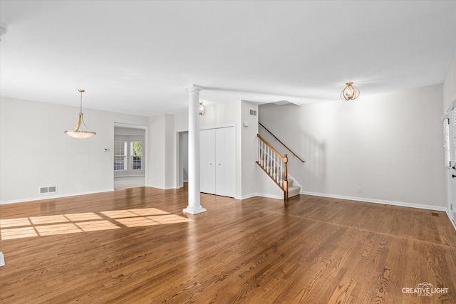 unfurnished living room featuring hardwood / wood-style flooring and decorative columns