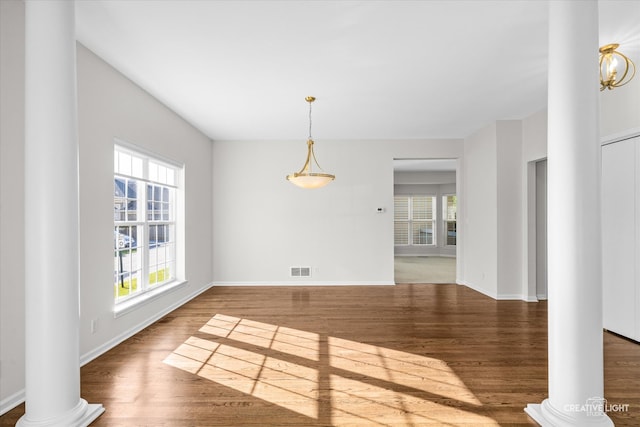 unfurnished dining area with decorative columns and dark hardwood / wood-style flooring