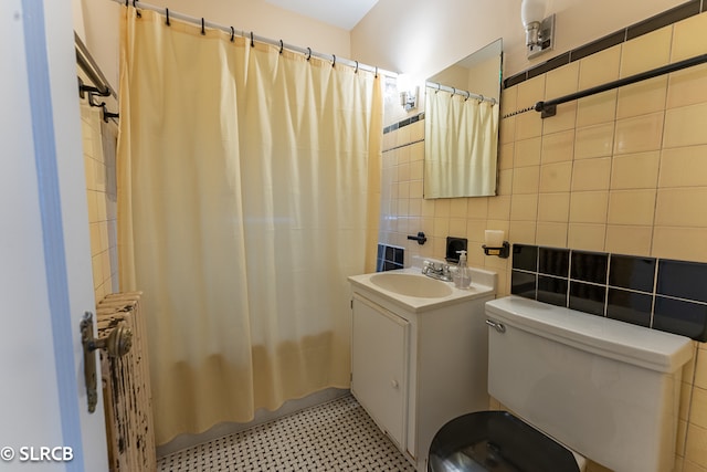 full bathroom with toilet, vanity, tile walls, radiator heating unit, and tasteful backsplash